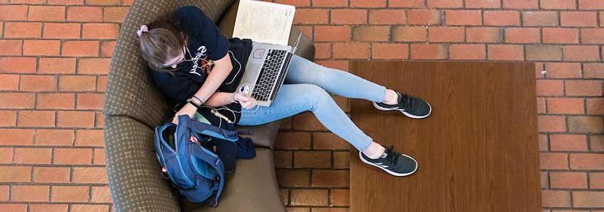 Student studying with laptop in lap.